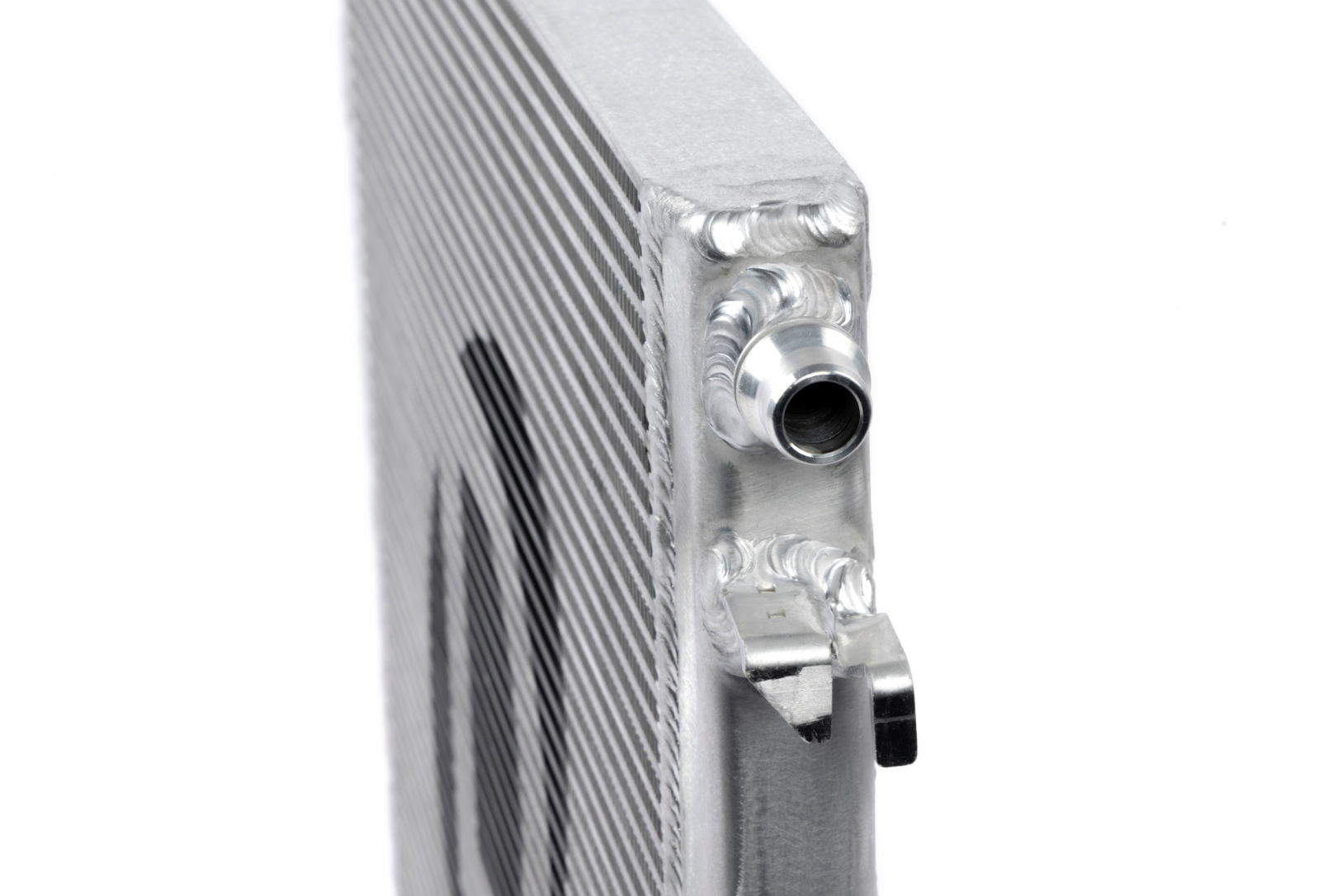 An extreme close-up of a silver metal heat exchanger highlighting the industrial welded seams and a cylindrical inlet pipe with a recessed groove.