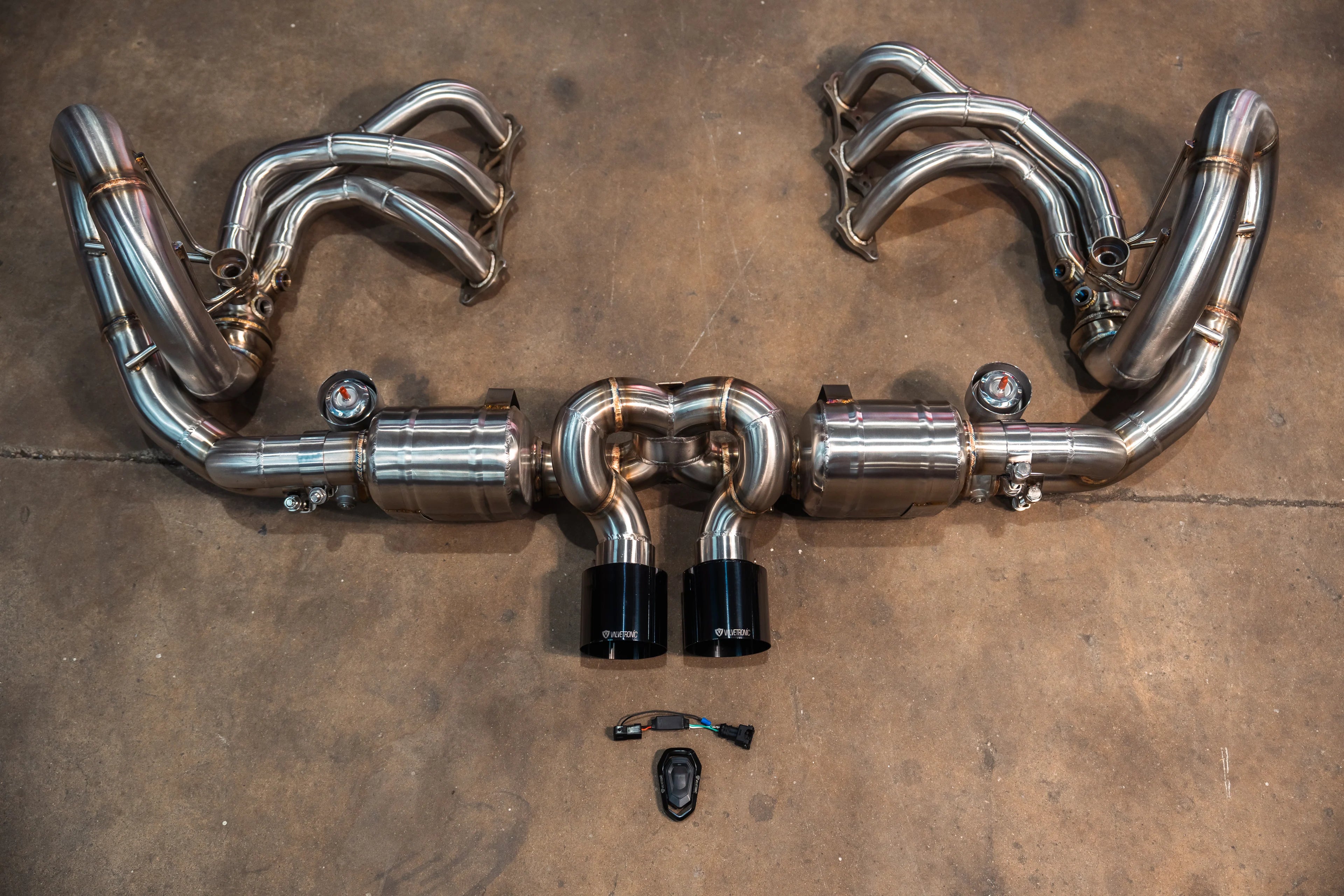Overhead view of the complete exhaust kit including the valved center muffler, stainless steel headers, and electronic valve control components.