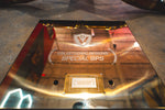 Extreme close-up of a reflective gold-finished plaque with "Valvetronic Designs Special Ops" and "McLaren 570S" engraved on it.