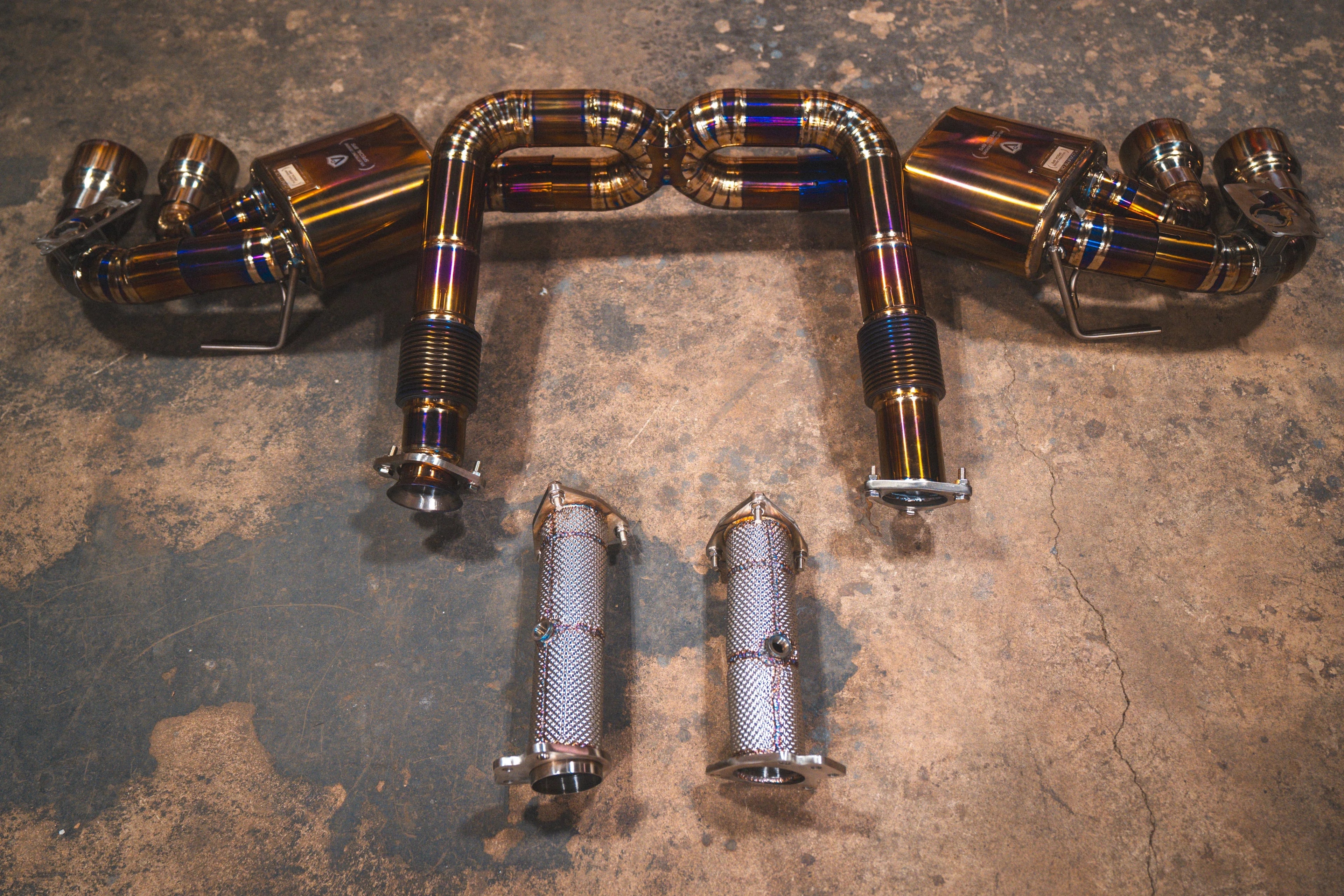 Rear-facing view of the titanium exhaust system highlighting the symmetrical layout, burnt-blue finish on the piping, and separate heat-shielded connector pipes.