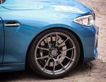 A close up view of a blue BMW with the front wheel fitted with AP Racing by Essex Radi-CAL ENP Competition Brake Kit (Front CP9660/372mm)- BMW F87 M2 & M2 Competition, F80 M3, F82 M4