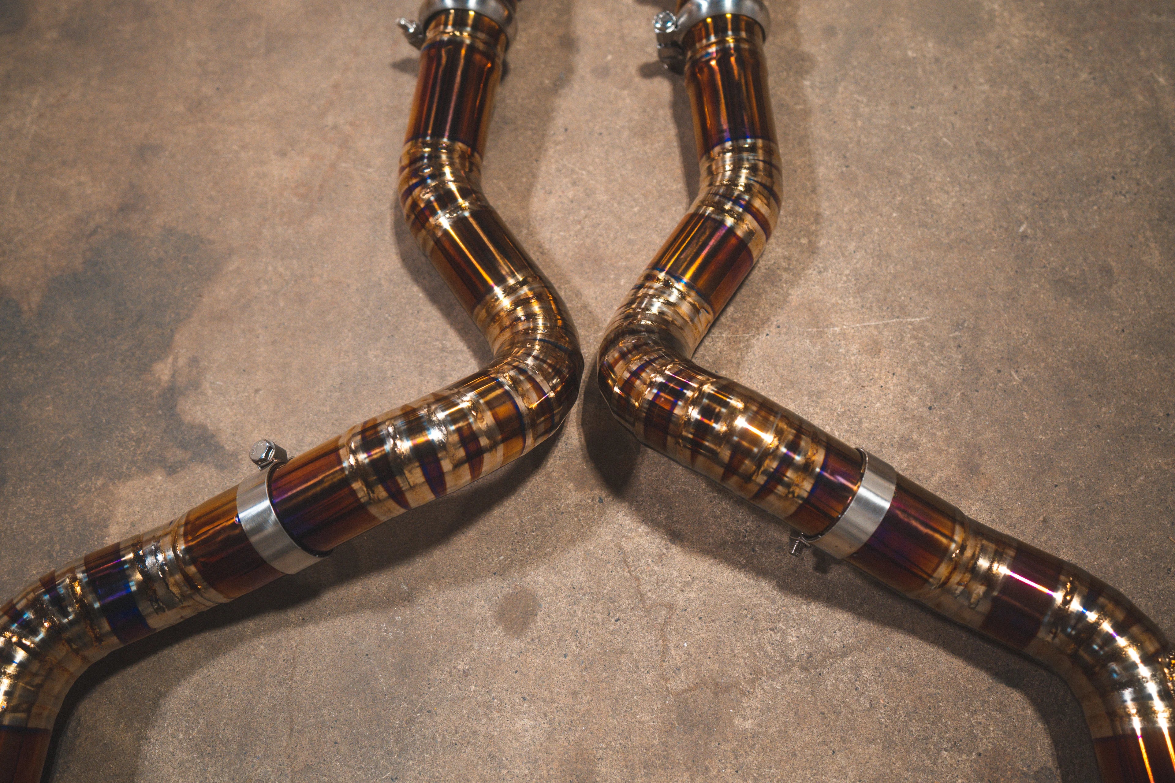 Close-up of the mid-pipe section highlighting the heat-tinted welds and metal securing clamps.