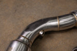 A close-up shot focusing on the mid-section of a Valvetronic Designs 400 Cell Catted Downpipe. 