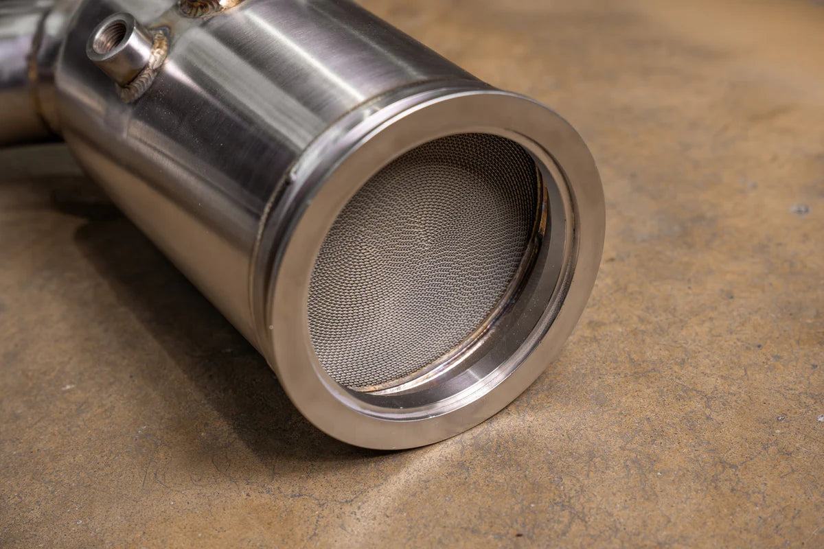 A close-up view of a Valvetronic Designs 400 Cell Catted Downpipe for a 2019-2022 Lamborghini Urus, highlighting the honeycomb structure.