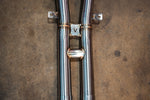 Close-up of the titanium crossover section featuring a Valvetronic Designs logo shield and support brackets.