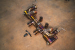 An angled overhead view of the gold-finish valved exhaust system showing the integrated valves and detailed TIG welding.