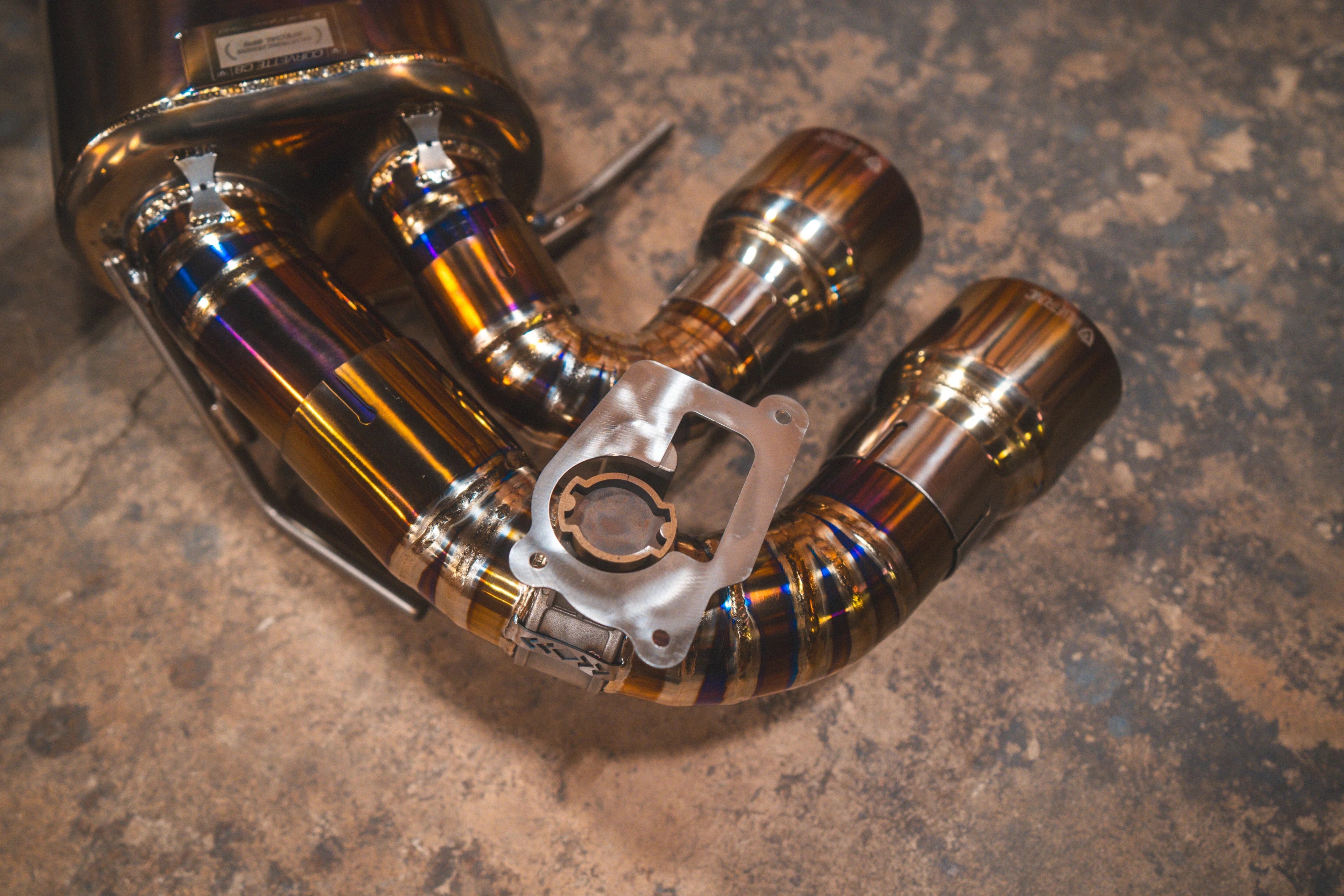 Close-up of the valved section and burnt titanium tips, featuring a raw metal valve mounting plate and high-quality weld beads.