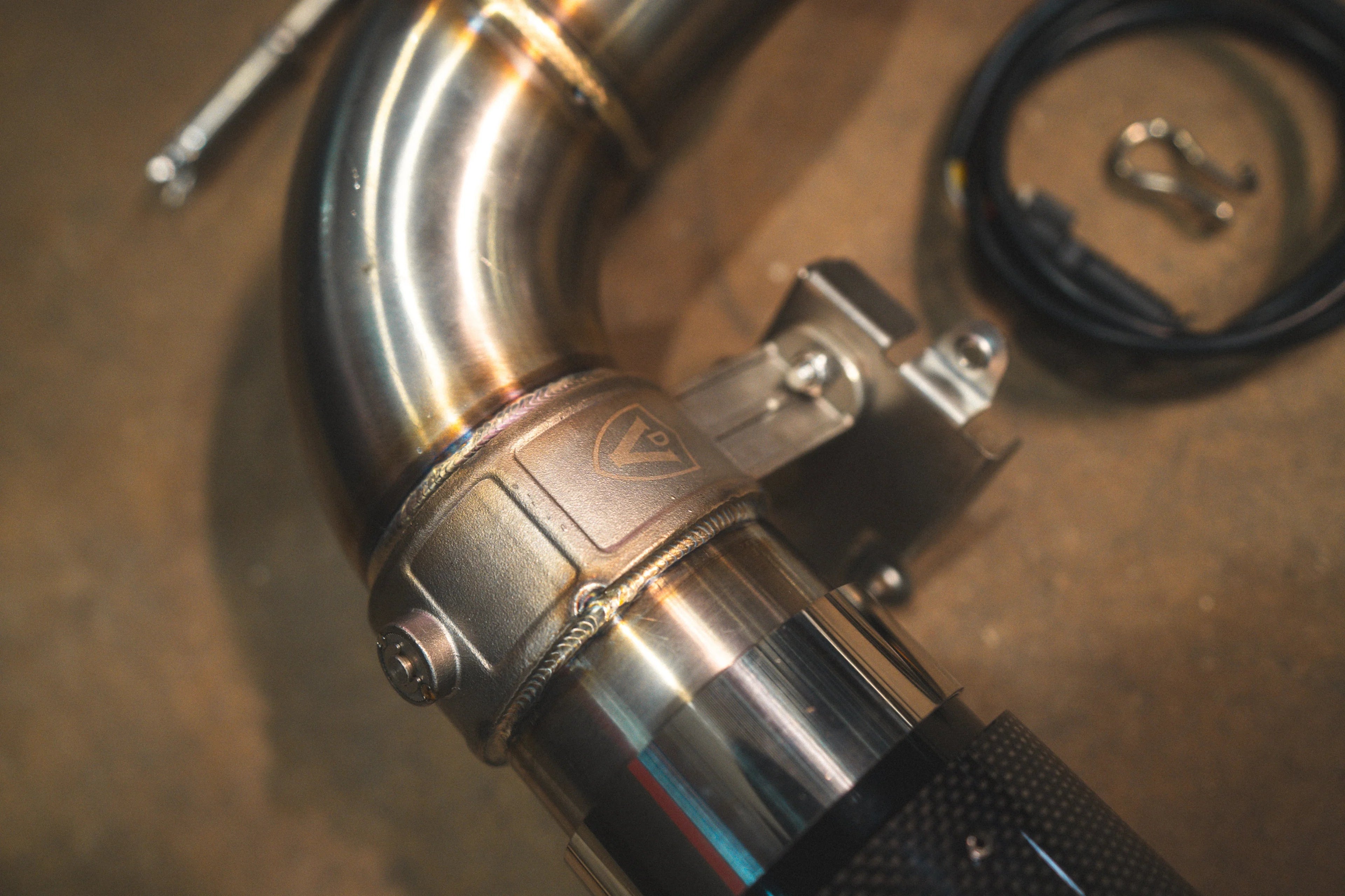 A close-up of the electronic valve actuator mechanism mounted on the exhaust piping, featuring an engraved Valvetronic shield logo