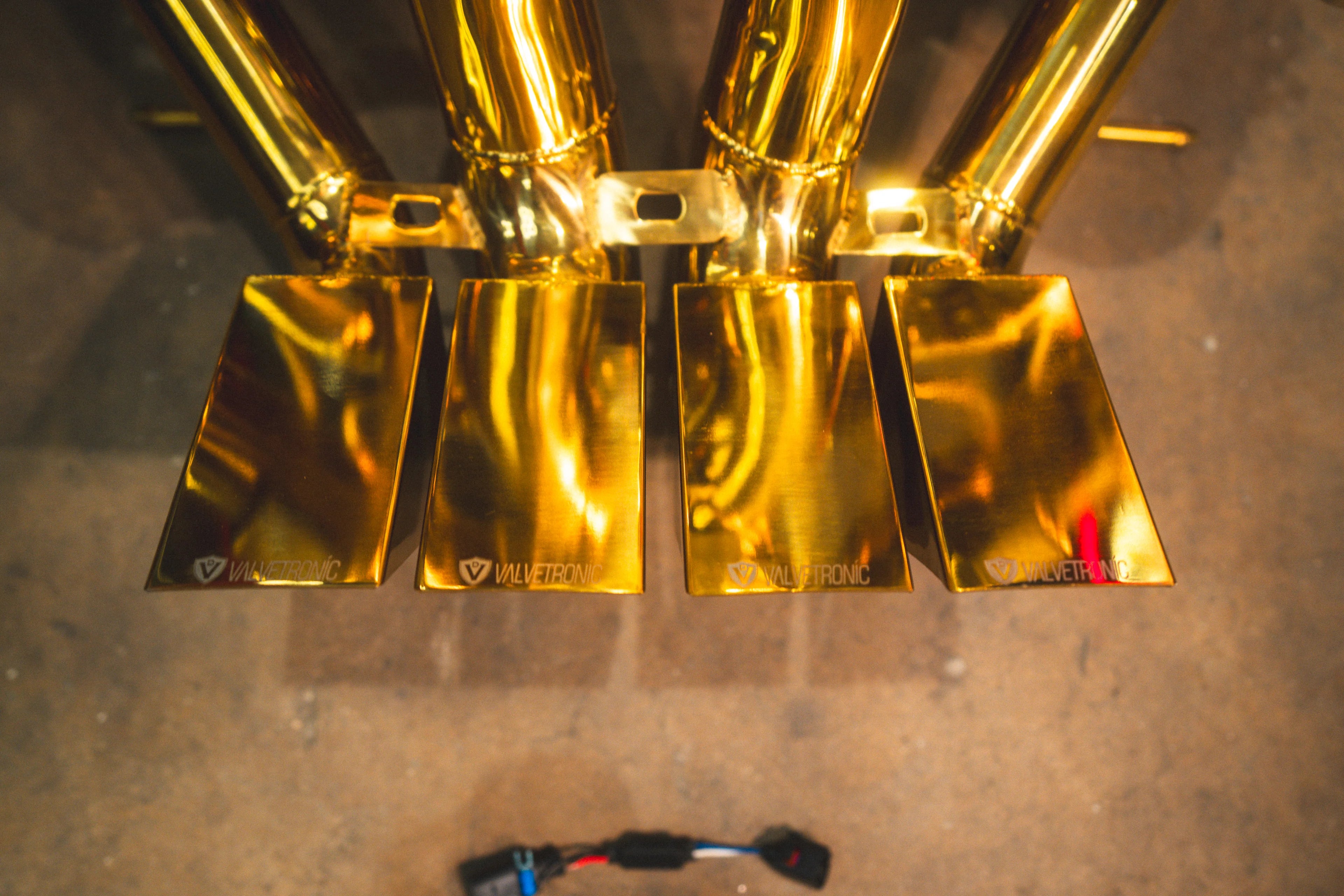 Top-down close-up view of the four gold-plated rectangular exhaust tips with etched Valvetronic branding.