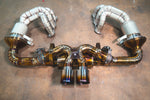 A view of the valved exhaust system connected to heat-shielded headers, highlighting the intricate weld patterns and titanium finish.