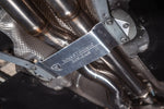 Close-up of the underside of a car showing the Valvetronic Designs branded metal brace supporting the exhaust piping.