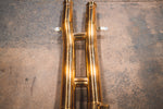 Top-down view of the gold-finish mid-pipe section showing the H-pipe crossover design and mounting brackets.