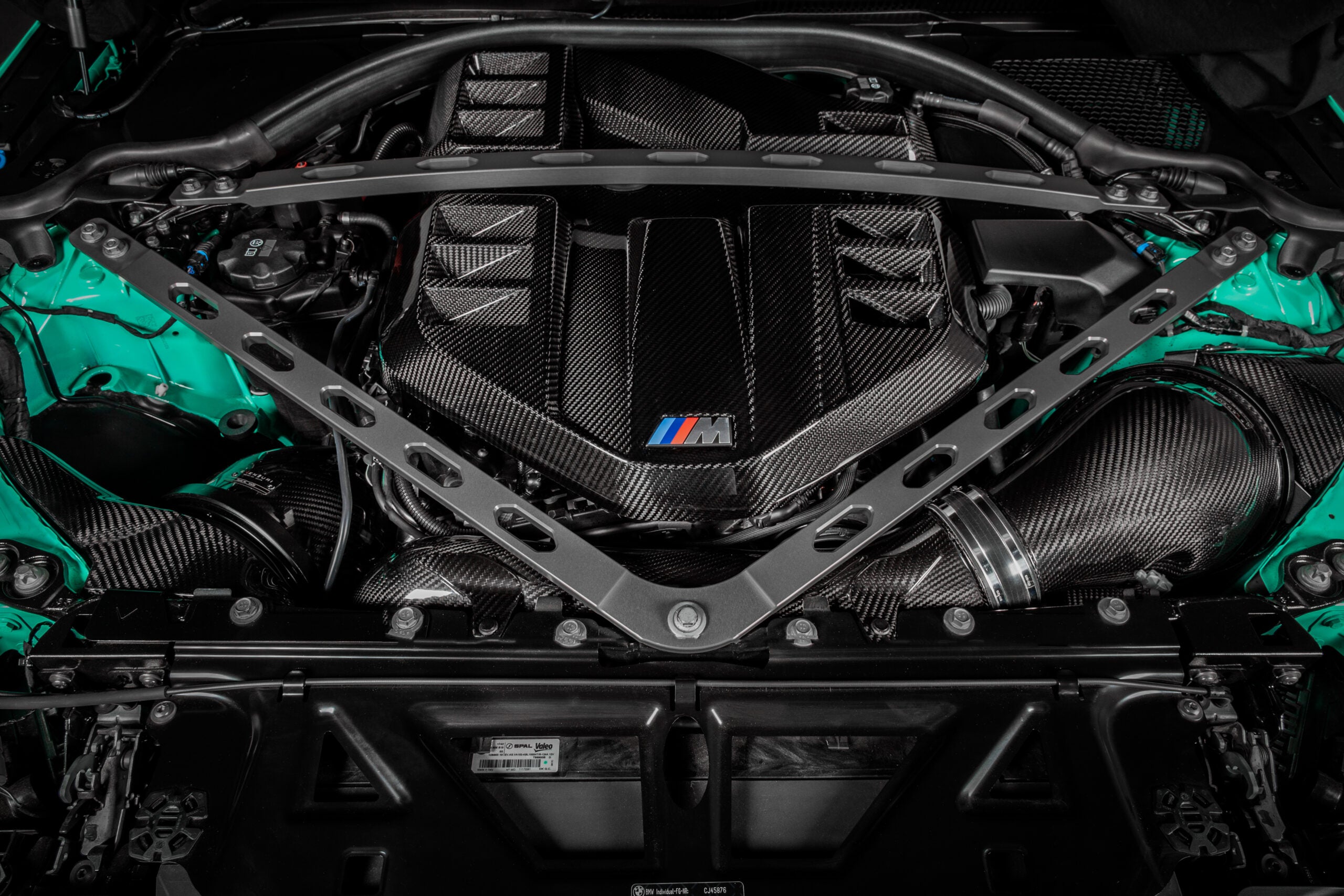 Top-down view of the Eventuri carbon cover installed in a mint green G8X M3 engine bay