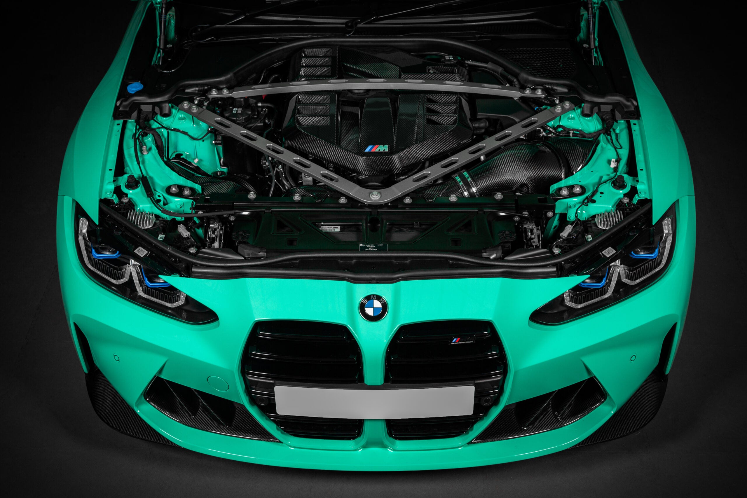 Front of a mint green BMW G8X with the hood up and the Eventuri carbon cover fitted
