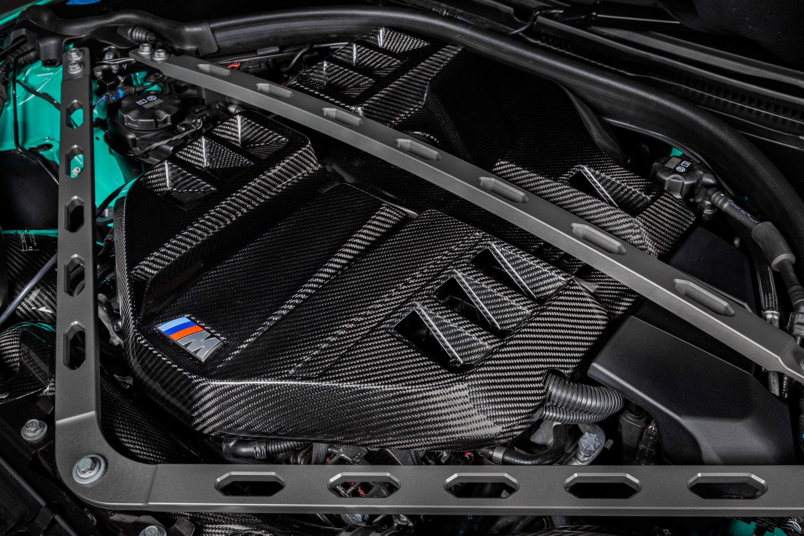 Close angled view of the installed Eventuri carbon cover with M badge below the strut brace