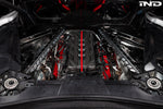 Black carbon fiber engine cover with red accent stripe installed in Corvette engine bay with visible components - Eventuri engine cover for Chevrolet Corvette