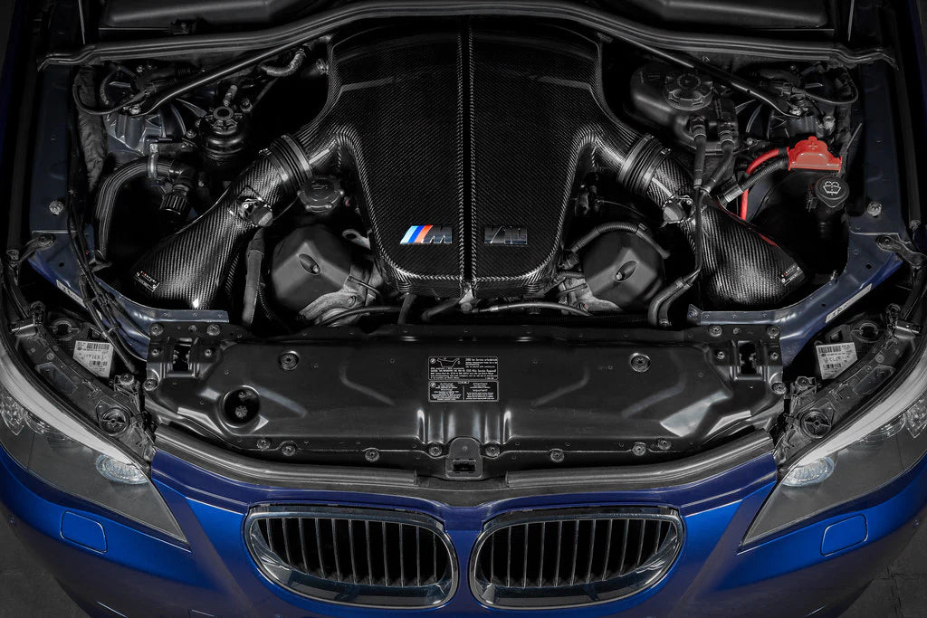 A top view of Eventuri Black Carbon Fiber Intake System V2 for BMW E60 M5 / E63 M6 2006-2010 fitted inside a blue car