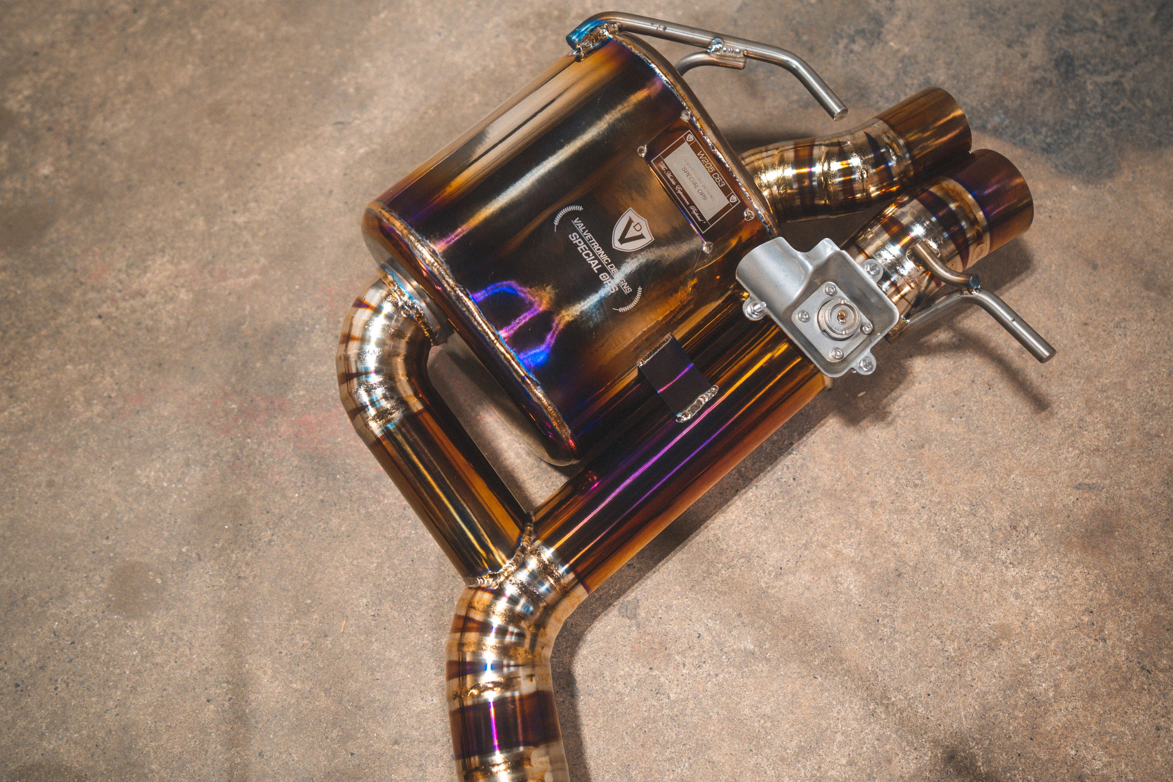 Overhead shot of a single rear muffler assembly featuring the Valvetronic Designs Special Ops plaque and electronic valve motor.