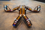 Rear-facing perspective of the titanium exhaust system, highlighting the symmetrical piping layout and dual exit tips.