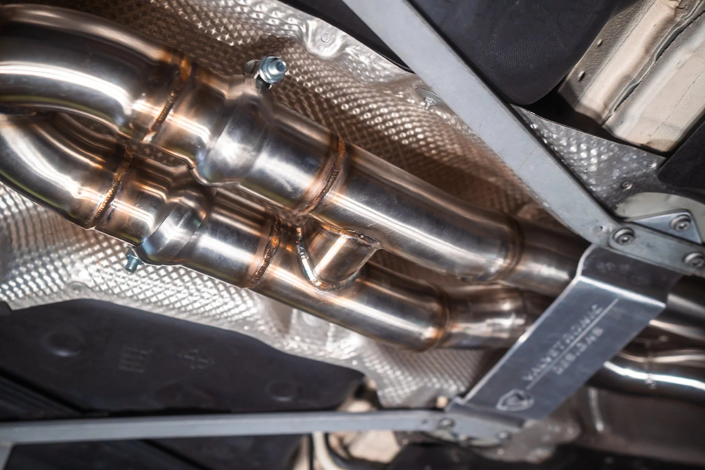 Detail shot of the equal length exhaust piping and welds on the underbody of a vehicle.