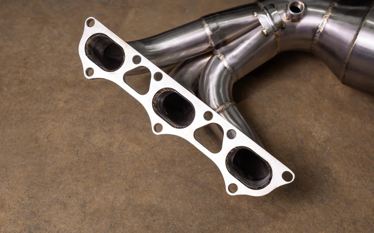 Detail view of the 10mm thick CNC-machined 3-bolt exhaust flange on Valvetronic Designs Porsche 992 GT3 headers, showing TIG-welded runners.