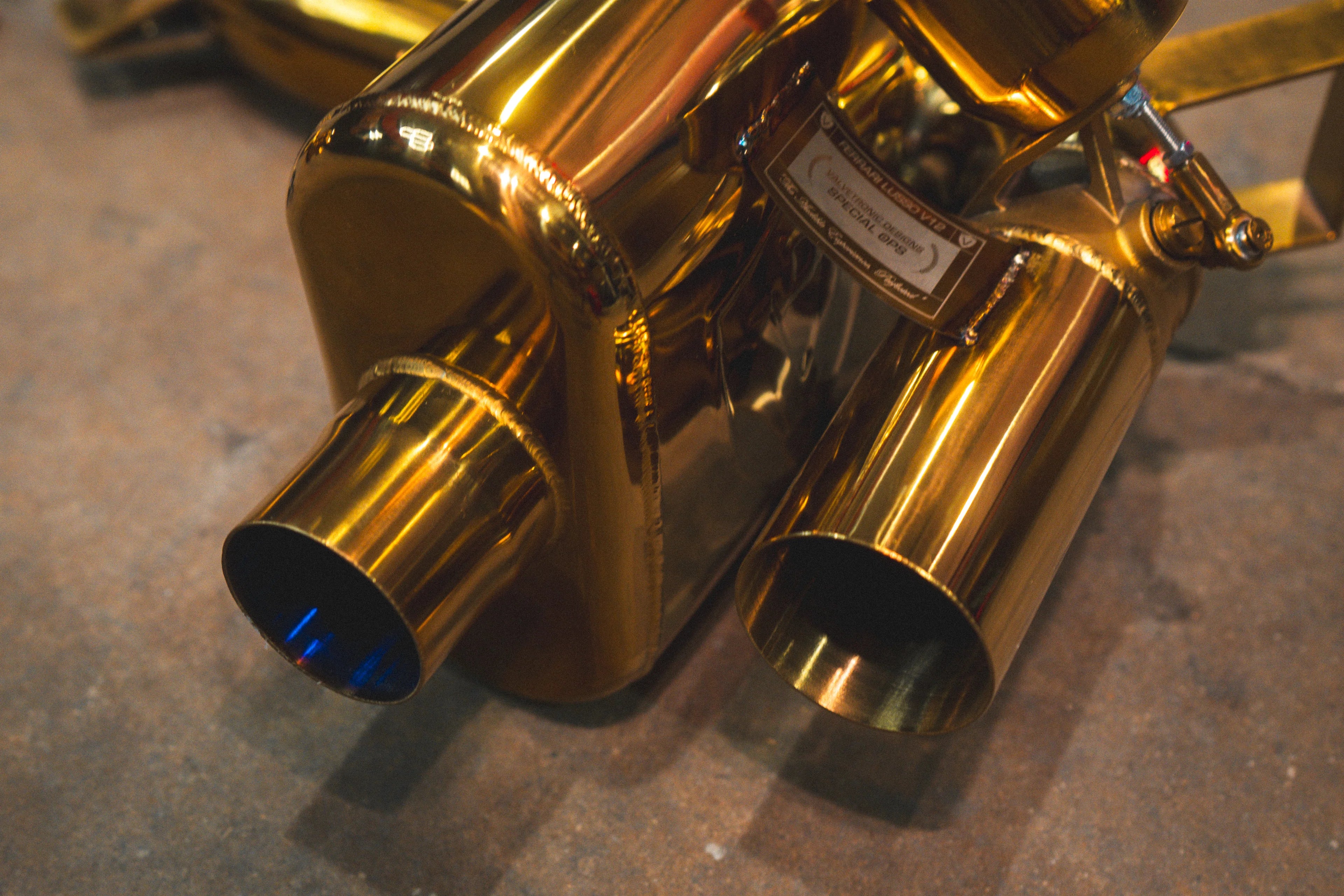 A detailed macro shot of the metal identification plaque engraved with "Ferrari Lusso V12," "Valvetronic Designs Special Ops," and "The Audible Experience, Perfected."