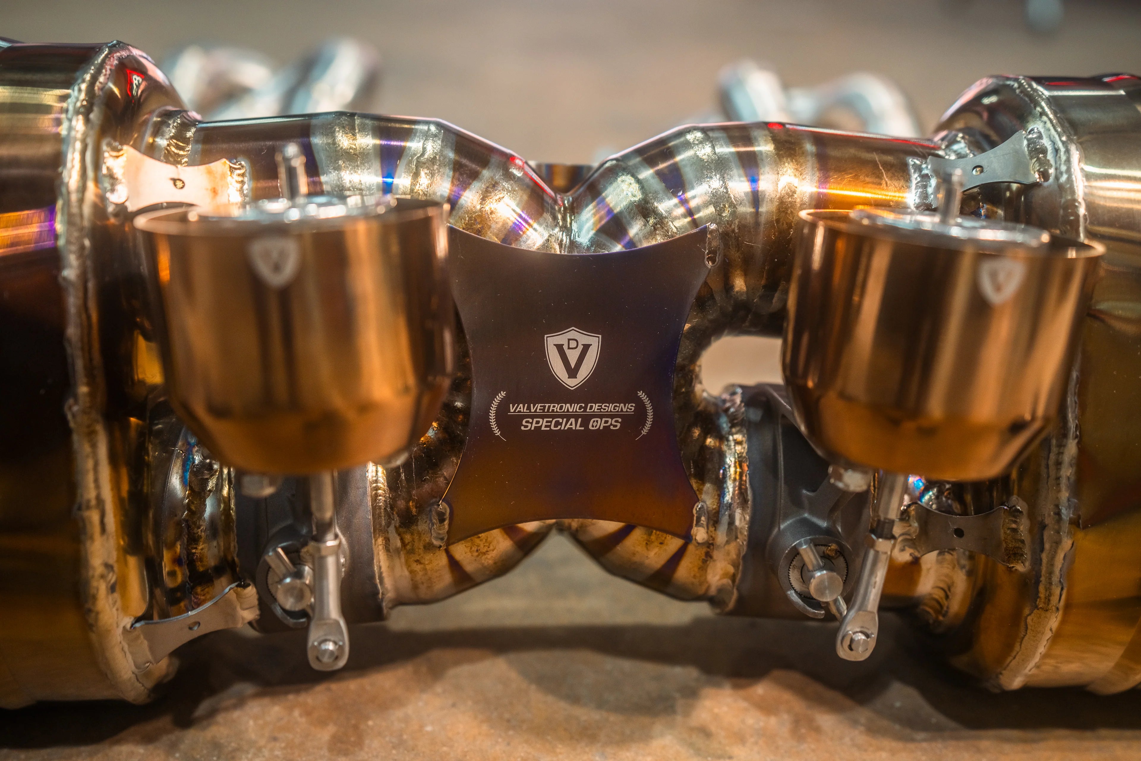 Detailed view of the exhaust center section featuring the Valvetronic Designs "Special Ops" logo and electronic valve actuators.