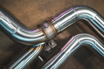 A detailed close-up of a vacuum or electronic actuator valve integrated into the exhaust piping, showing the mechanical linkage and surrounding TIG welds.