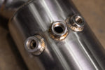 Detailed close-up of the Valvetronic Designs 400 Cell Catted Downpipe for the 2019-2022 Lamborghini Urus, showing three high-quality TIG-welded O2 sensor bungs on a brushed stainless steel surface.