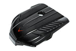 Black carbon fiber engine cover with angular sculptured design, central circular opening, and integrated ventilation slats - Eventuri engine cover for Toyota Supra