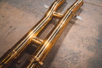 Perspective view of the dual mid-pipes showing the reflective gold finish and structural support braces.