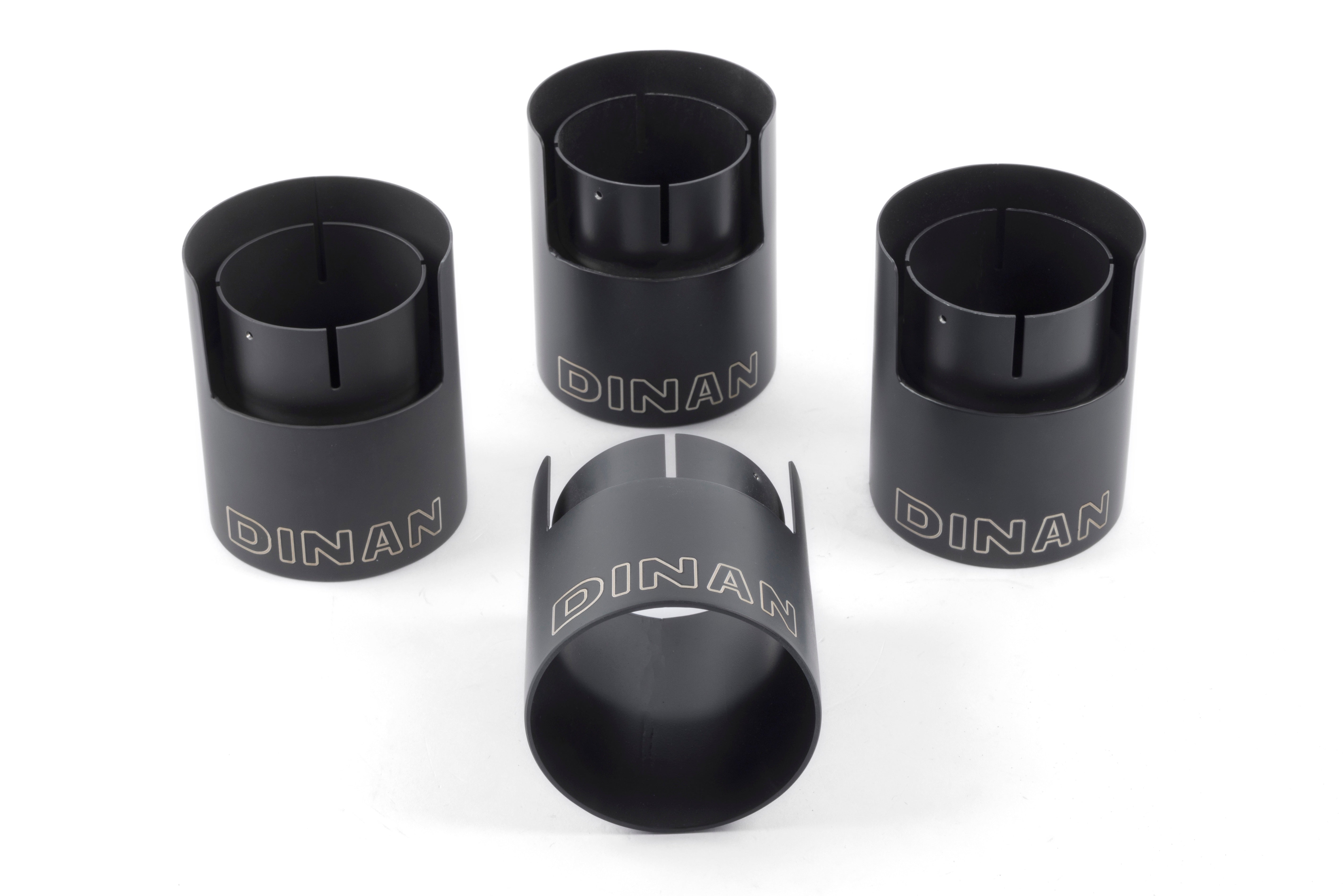 A detailed close-up of the four 4-inch exhaust tips for the Dinan X3 M40i exhaust. The tips feature a stealthy matte black ceramic-coated finish, a double-walled design, and the Dinan logo laser-engraved on the top of each tip.