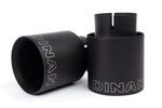 A close-up view of the two black ceramic coated exhaust tips. The image highlights the double-walled, slant-cut design with a mirror finish and the laser-etched Dinan logo on the top of each tip.