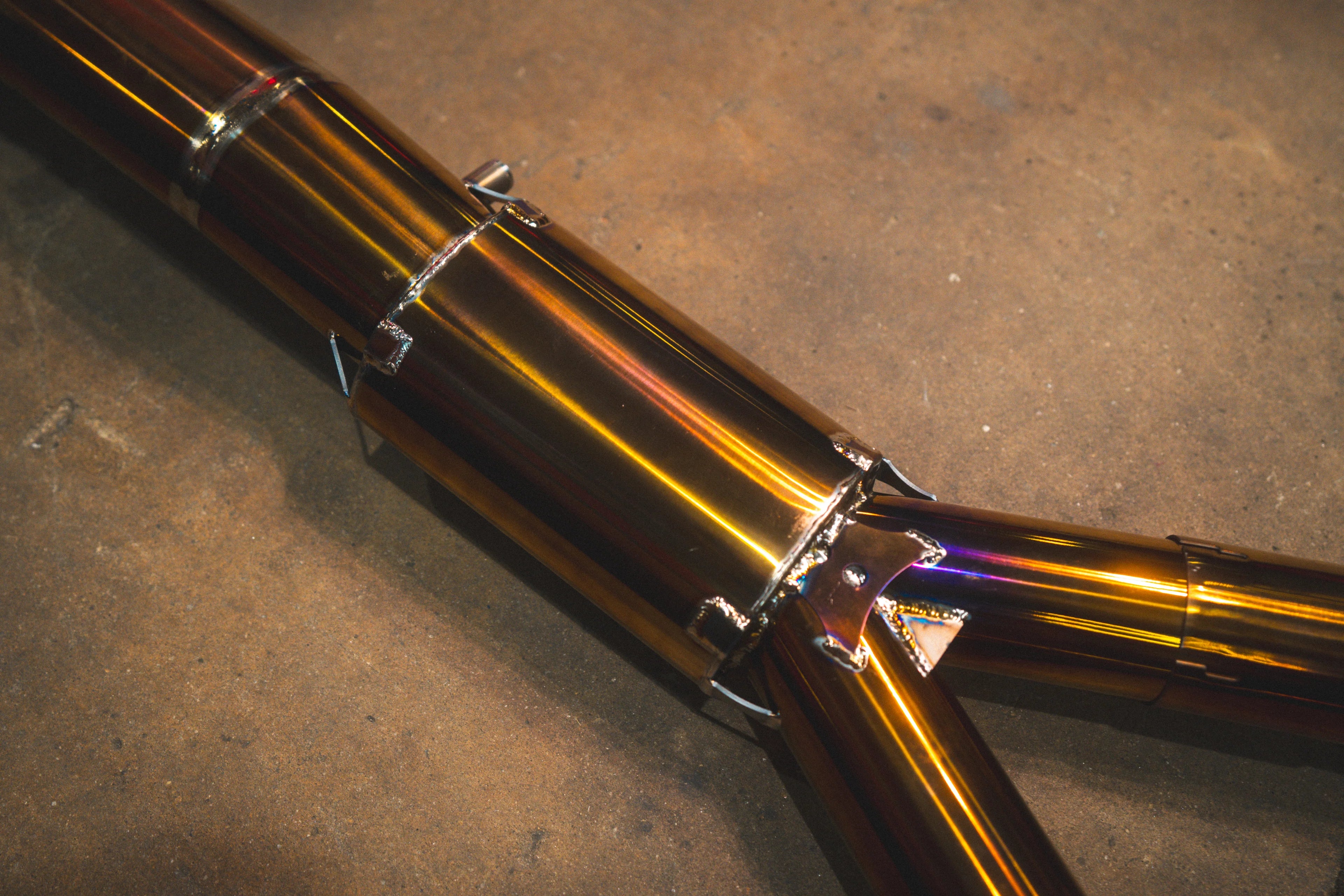 A detailed shot of a pipe junction on the titanium system, showing a reinforcement plate with triangular cutouts and specialized TIG welding.