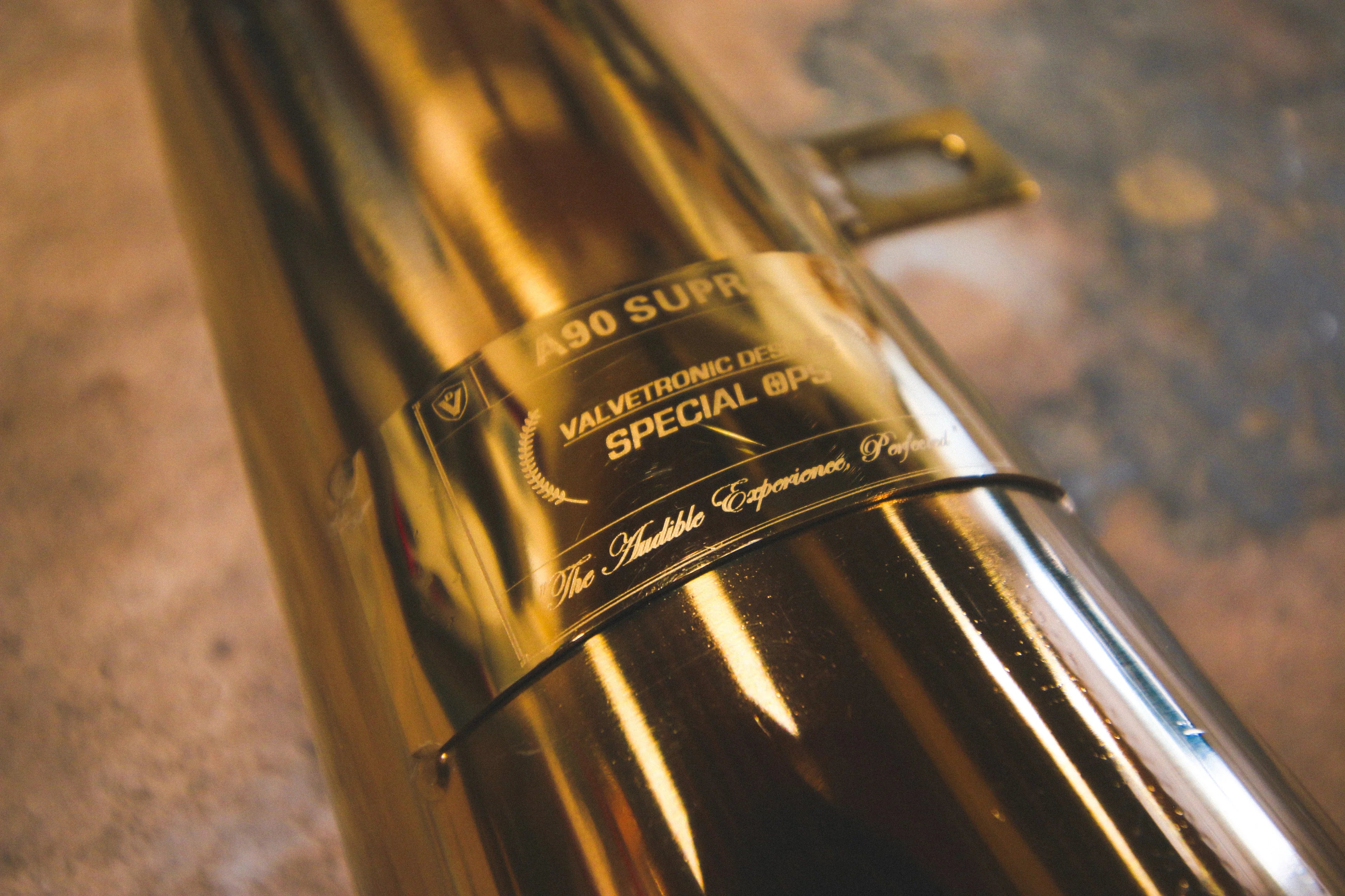 Macro close-up of the "Special Ops" identification plate riveted to the exhaust piping, featuring the Valvetronic Designs branding and "A90 Supra" text.