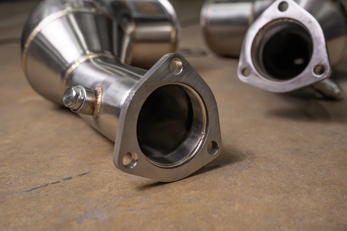 Close-up of Valvetronic Designs Audi C8 RS6/RS7 catted downpipe showing the precision-machined 3-bolt flange, T304 stainless steel construction, and welded O2 sensor bung.