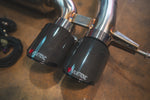 Macro view of two carbon fiber exhaust tips featuring the Valvetronic Designs logo.