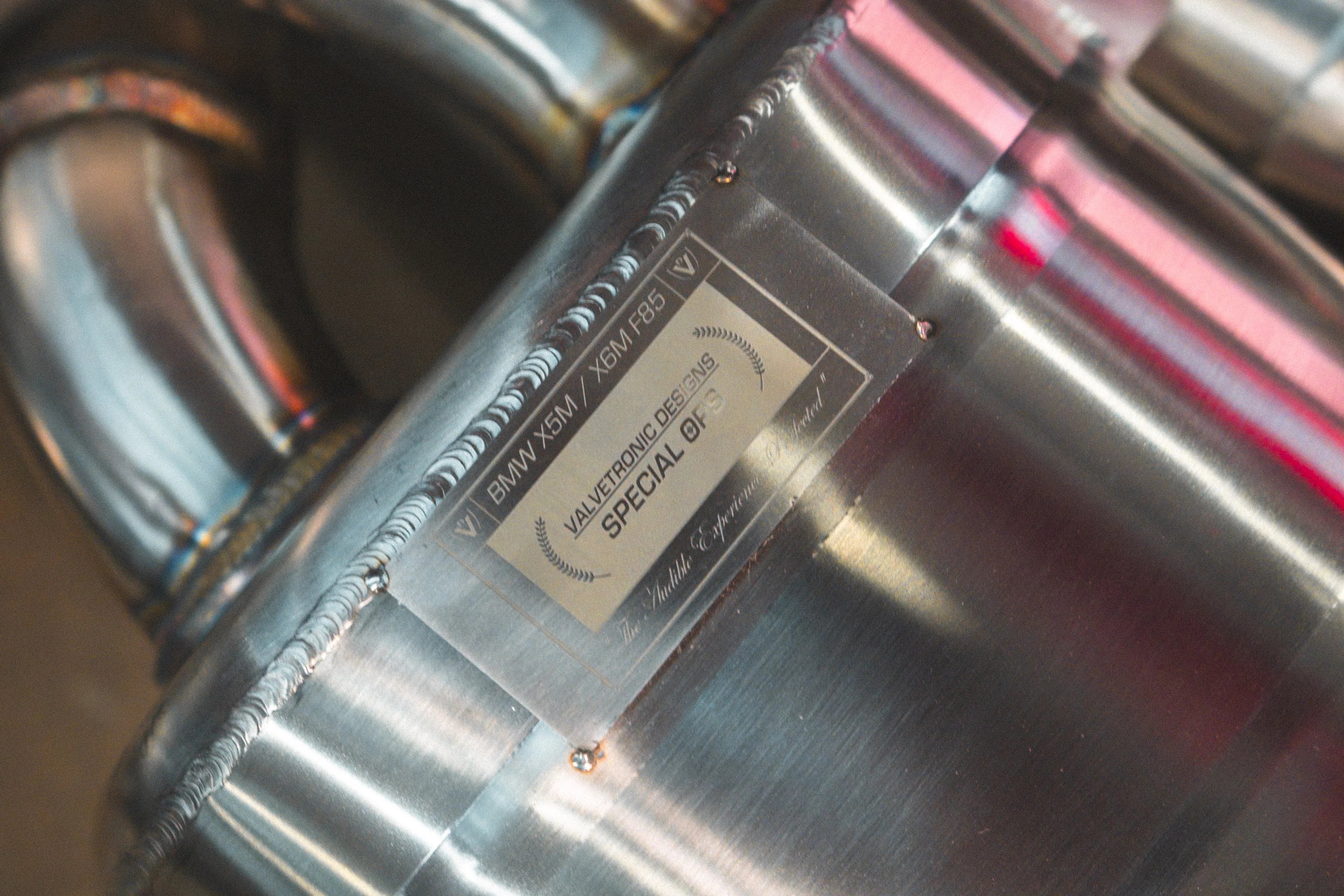 Close-up of the engraved authenticity plaque on the muffler body reading "Valvetronic Designs Special Ops" for BMW X5M / X6M F85.