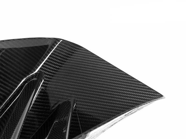 A close up view of AUTOTECKNIC DRY CARBON CORSA FRONT AIR INLET TRIM SET - BMW G87 M2 2023+ with white background
