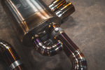 Close-up of the titanium muffler's high-quality TIG welds and the vacuum-actuated valve mechanism on the bypass pipe.