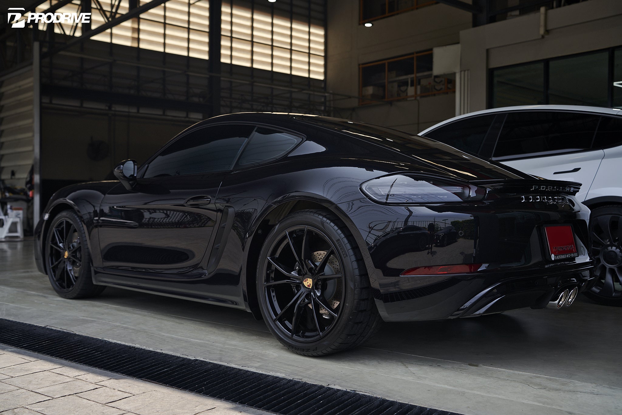 Black Porsche 718 Cayman fitted with an IPE exhaust, rear three-quarter view