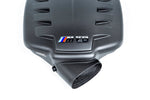 Carbon fiber inlet plenum with angular design, ventilation slits, and curved intake tube on white background - Eventuri inlet plenum for BMW M3