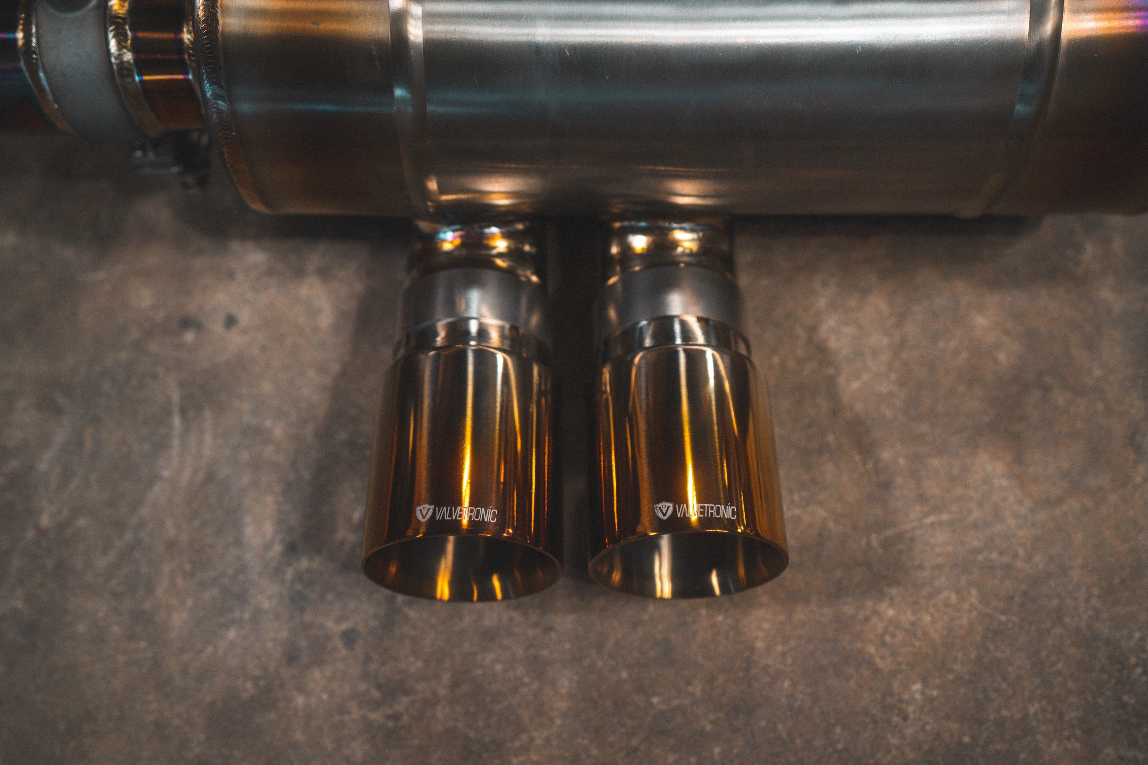 Direct top-down view of the dual exhaust tips integrated into the titanium muffler, showing the etched Valvetronic branding.