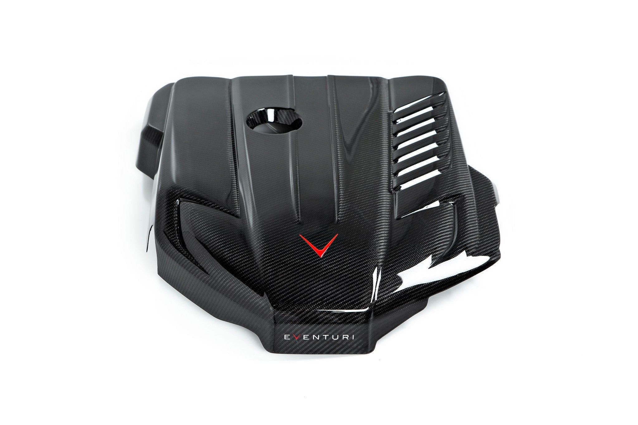Black carbon fiber engine cover with angular design featuring ventilation slots and red accent detail - Eventuri engine cover for Toyota Supra