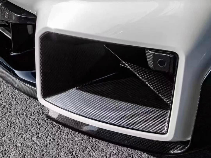 A close up view of AUTOTECKNIC DRY CARBON FRONT AIR INLET TRIM SET - BMW G87 M2 2023+ fitted on a car