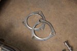 Close-up view of a pair of multi-layer steel (MLS) exhaust gaskets included with Valvetronic Designs 400 Cell Catted Downpipes for a 2019-2022 Lamborghini Urus.