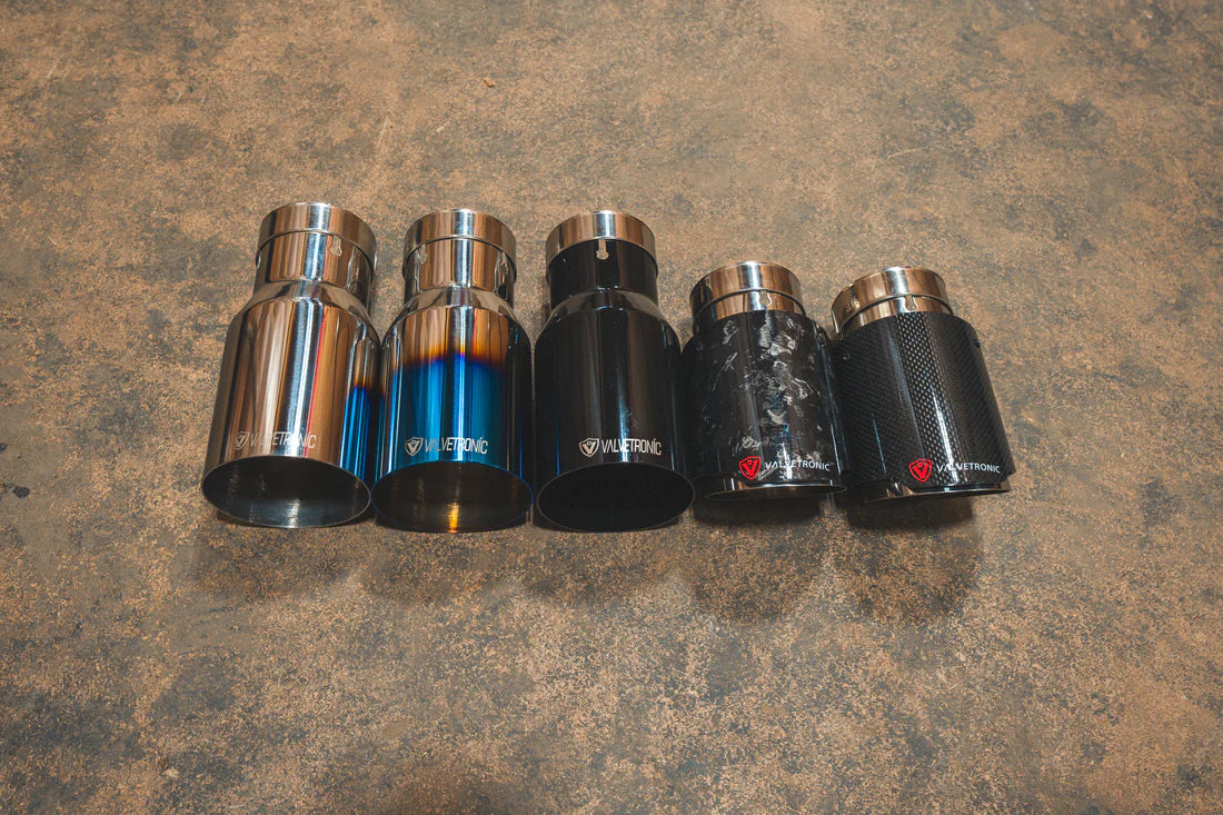 A top view of a five different styles of Valvetronic Designs Exhaust Tips on the ground.