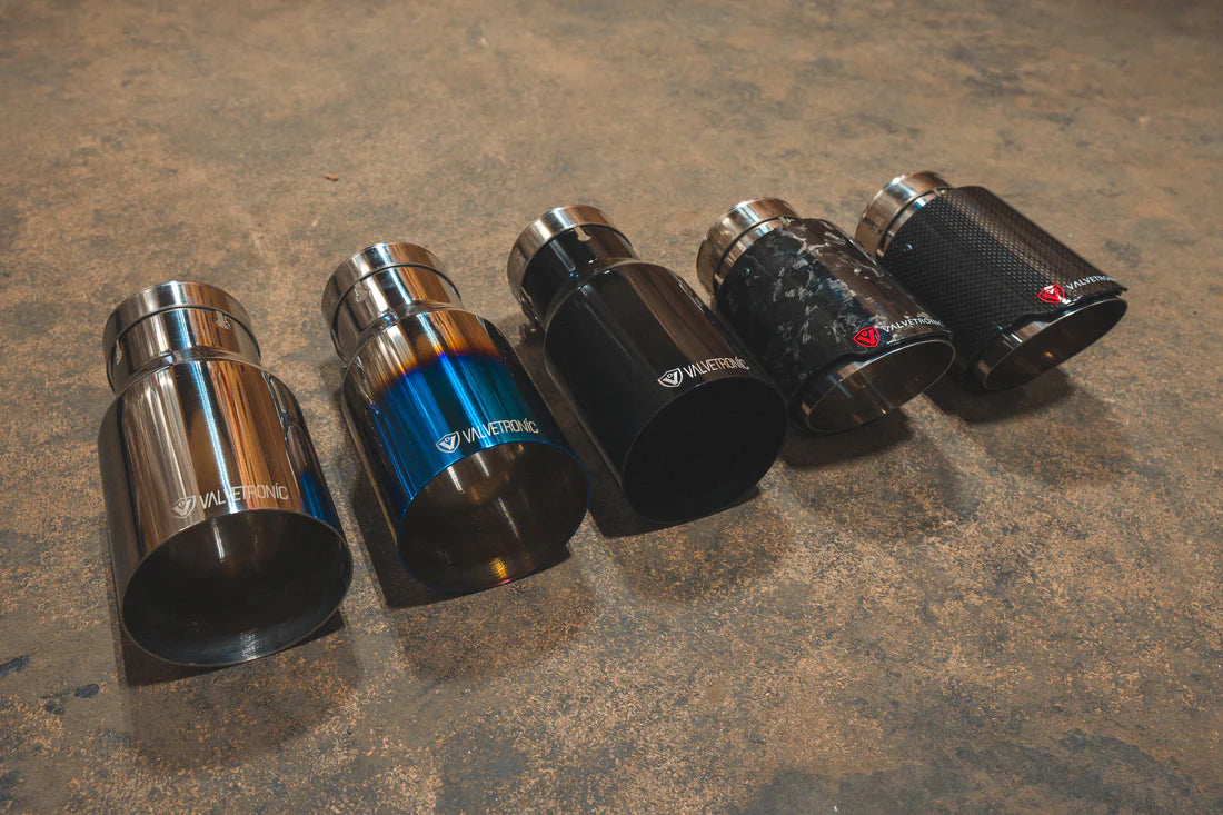 A side view of a five different styles of Valvetronic Designs Exhaust Tips on the ground.