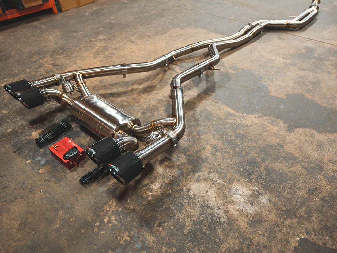 A side view of Valvetronic Designs Valved Sport Exhaust System with wires and a small red box on the ground (for BMW F87 M2). 