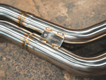 A close view of a part of Valvetronic Designs Valved Sport Exhaust System, showing the brand's logo, on the ground (for BMW F87 M2).